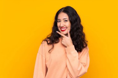 İspanyol Çinli kadın izole edilmiş sarı arka planda gülümsüyor