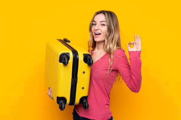 度假时 年轻女子背着旅行箱 在孤立的黄色背景上签了个 — 图库照片