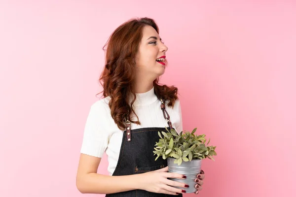 Giovane Donna Russa Sfondo Rosa Isolato Prendendo Vaso Fiori — Foto Stock