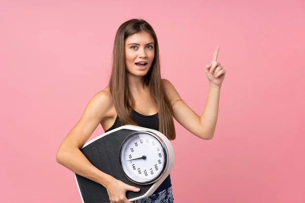 Chica joven con máquina de pesaje sobre fondo rosa aislado — Foto de Stock