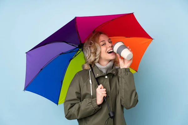 Femme tenant un parapluie isolé sur fond bleu — Photo