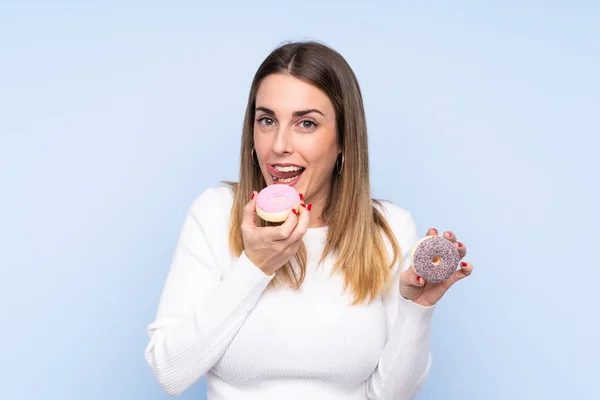 Junge Blonde Frau Über Isoliertem Blauem Hintergrund Mit Einem Donut — Stockfoto