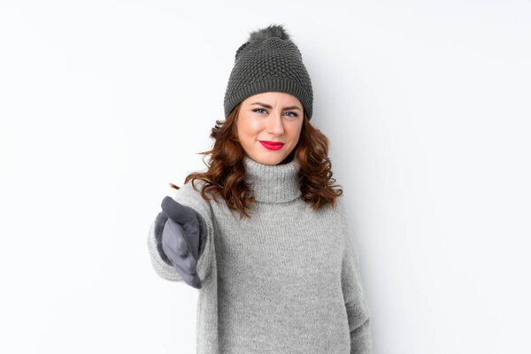 Young Russian woman with winter hat over isolated white background handshaking after good deal