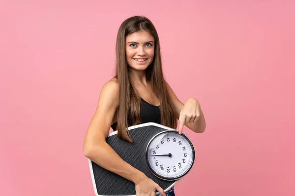 Menina com máquina de pesagem sobre fundo rosa isolado — Fotografia de Stock