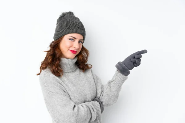 年轻的俄罗斯女人 头戴冬帽 独立的白色背景 手指指向侧面 — 图库照片