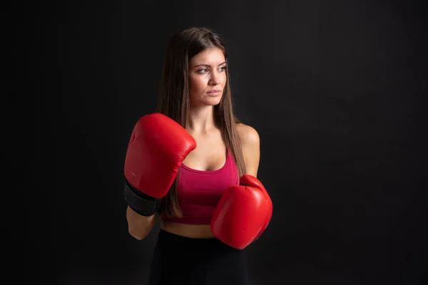 Jovem mulher esporte com luvas de boxe sobre fundo preto isolado — Fotografia de Stock