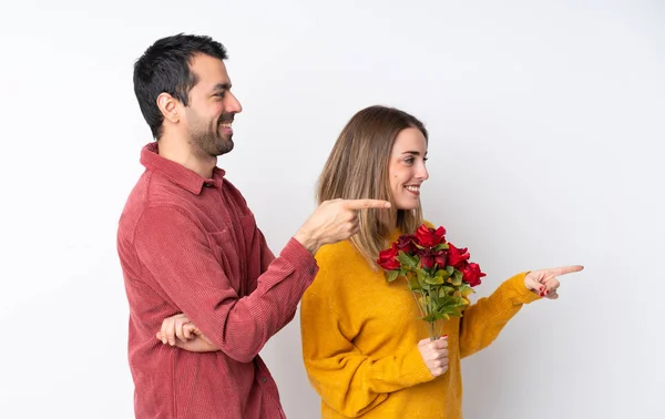 Pár Valentýna Drží Květiny Přes Izolované Pozadí Ukazující Prstem Stranu — Stock fotografie