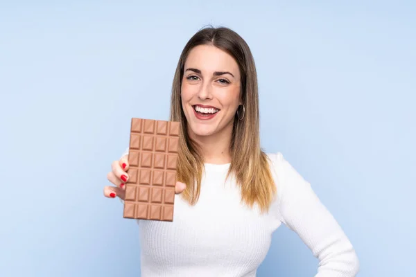 Junge Blonde Frau Über Isolierten Blauen Hintergrund Nimmt Eine Schokoladentablette — Stockfoto