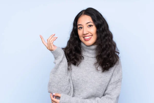 Spaanse Chinese Vrouw Geïsoleerde Blauwe Achtergrond Reikende Handen Aan Zijkant — Stockfoto