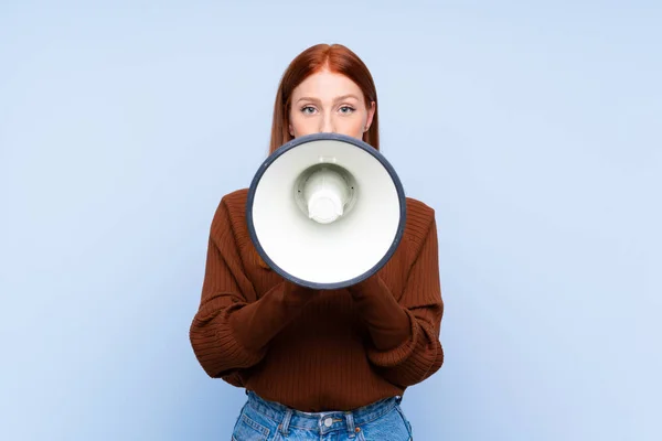 Jonge Roodharige Vrouw Geïsoleerde Blauwe Achtergrond Schreeuwen Door Een Megafoon — Stockfoto