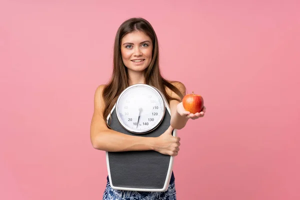 Ung flicka med våg maskin och med ett äpple över isolerad — Stockfoto