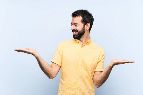 Young Man Beard Isolated Blue Background Holding Copyspace Two Hands — Stock Photo, Image