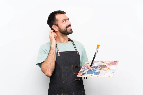 年轻的艺术家男人拿着调色板在孤立的背景下思考着一个想法 — 图库照片