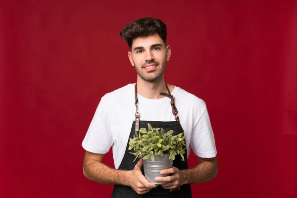 Jongeman Geïsoleerde Achtergrond Nemen Van Een Bloempot — Stockfoto