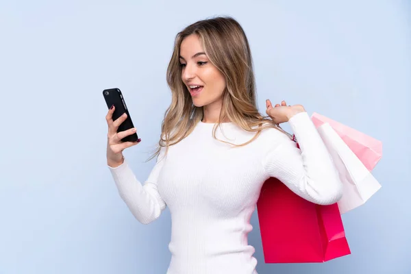 Mujer Joven Sobre Fondo Azul Aislado Sosteniendo Bolsas Compras Escribiendo —  Fotos de Stock