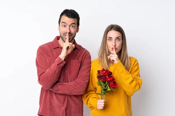 バレンタインデーのカップル保持花上の隔離された背景を示す沈黙ジェスチャーの印で指で口 — ストック写真