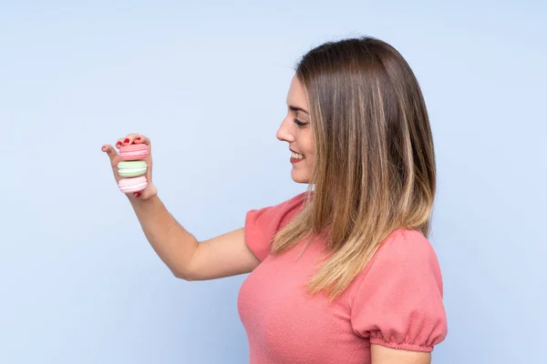 Fiatal Szőke Felett Elszigetelt Kék Háttér Gazdaság Színes Francia Macarons — Stock Fotó