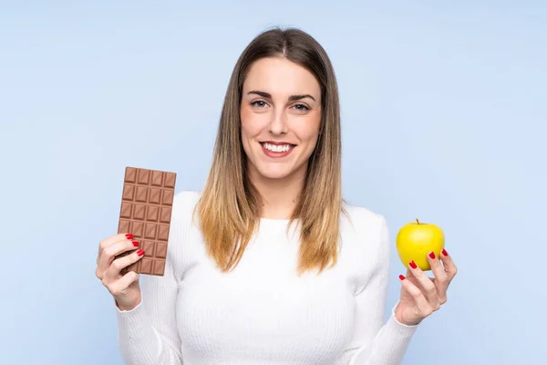Mladá Blondýna Žena Izolovaném Modrém Pozadí Přičemž Čokoládovou Tabletu Jedné — Stock fotografie