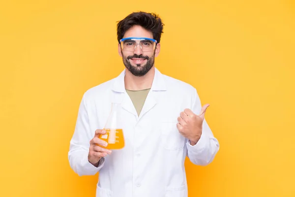 Joven Científico Sobre Fondo Amarillo Aislado Apuntando Hacia Lado Para — Foto de Stock