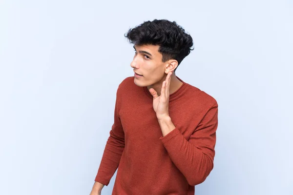 Joven Argentino Sobre Fondo Azul Aislado Escuchando Algo Poniendo Mano —  Fotos de Stock