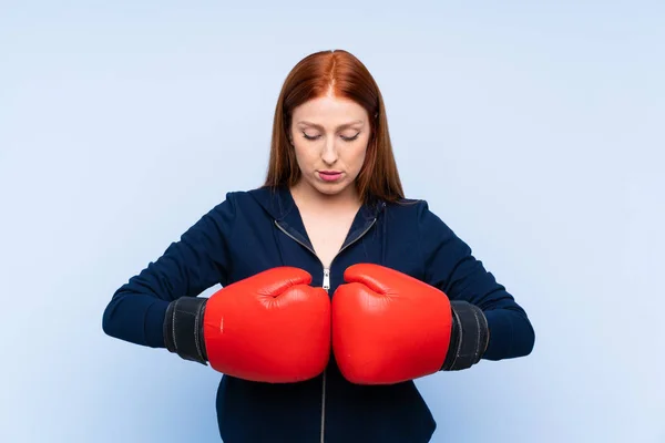 若いですRedheadスポーツ女性以上隔離された青の背景でボクシング手袋 — ストック写真