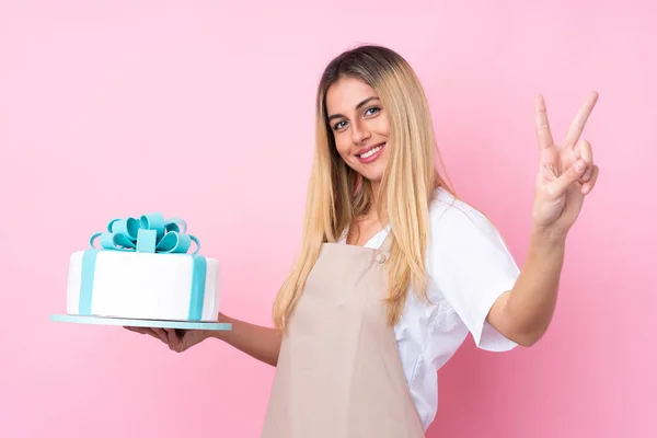 Joven Pastelera Uruguaya Con Gran Pastel Sobre Fondo Rosa Aislado — Foto de Stock