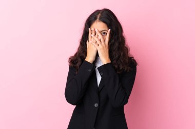 Karmaşık ırk işkadını pembe arka planda gözleri kapatıyor ve parmaklarından bakıyor.