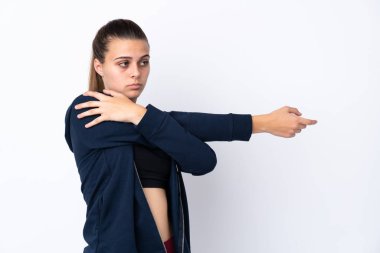 İzole edilmiş beyaz arka planda kollarını esneten genç bir spor kızı.