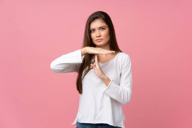 Soyutlanmış pembe arka planda genç bir kadın zaman aşımı hareketi yapıyor.