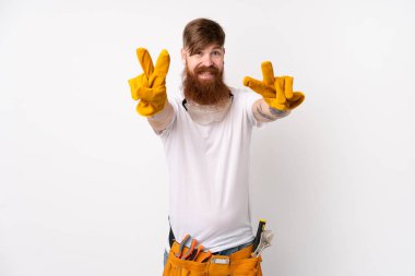 Uzun sakallı kızıl saçlı elektrikçi izole edilmiş beyaz arka planda gülümsüyor ve zafer işareti gösteriyor.