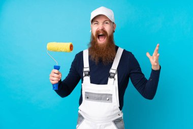 Uzun sakallı ressam, izole edilmiş mavi arka planda mutsuz ve hayal kırıklığına uğramış.