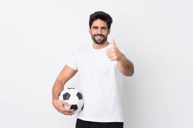 Sakallı, genç, yakışıklı, soyutlanmış, beyaz bir geçmişi olan, futbol topu olan ve başparmağı havada genç bir adam.