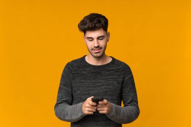 İzole edilmiş arka plan üzerinde genç adam cep telefonuyla bir mesaj ya da e-posta gönderiyor
