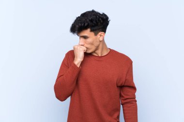 Arjantinli genç adam soyutlanmış mavi arka planda şüpheleri var.