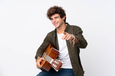 İzole edilmiş beyaz arka plan üzerinde gitarı olan genç beyaz bir adam sana işaret ediyor.
