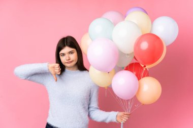 Genç Ukraynalı kız, pembe arka planda bir sürü balon tutuyor.