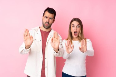 Sevgililer Günü 'nde bir çift, pembe arka plan yüzünden hayal kırıklığına uğradıkları için durdurma hareketi yapıyor.