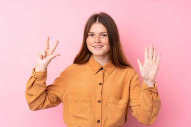 İzole edilmiş pembe arka planı olan Ukraynalı genç kız parmaklarıyla sekiz sayıyor.