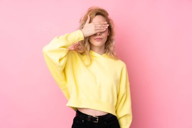 Pembe arka planda izole edilmiş eşofman üstü giyen genç sarışın kadın gözlerini elleriyle kapatıyor. Bir şey görmek istemiyorum.