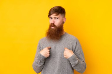 Kızıl saçlı, uzun sakallı, izole edilmiş sarı arka planı olan bir adam kendini işaret ediyor.