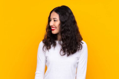 Karışık ırk kadını, izole edilmiş sarı arka planda yan tarafa bakıyor.