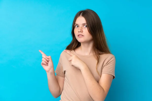 Ucraniano Adolescente Chica Sobre Aislado Azul Fondo Asustado Señalando Lado —  Fotos de Stock