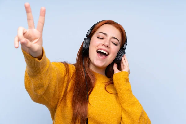 Roodharige Tiener Meisje Geïsoleerde Blauwe Achtergrond Luisteren Muziek Zingen — Stockfoto