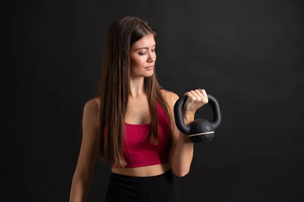 Молода спортивна жінка робить важку атлетику над ізольованим чорним тлом — стокове фото
