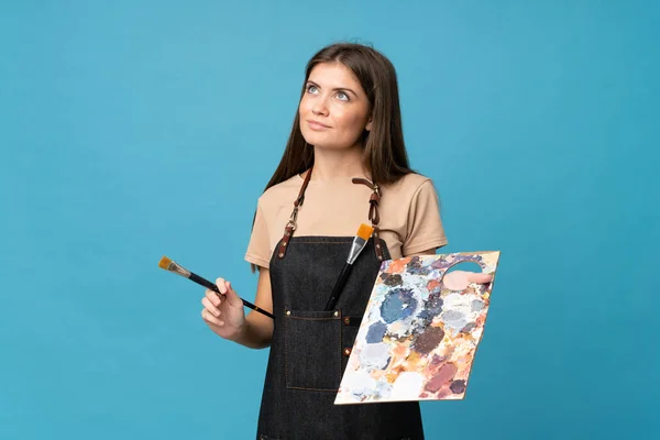 Soyutlanmış Mavi Arka Planda Genç Bir Kadın Palet Tutuyor Bir — Stok fotoğraf