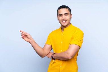 Asyalı yakışıklı adam izole edilmiş arka planda parmağını yana doğru gösteriyor.