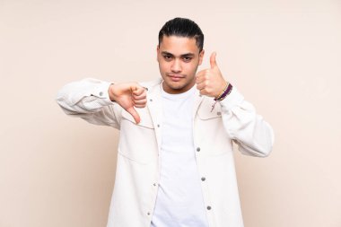 Tecrit edilmiş Asyalı yakışıklı adam iyiye-kötüye işaret yapıyor. Evet ya da hayır arasında kararsız