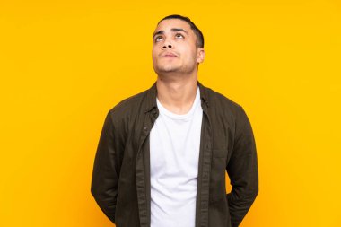 Asyalı yakışıklı adam sarı arka planda izole edilmiş bir fikir düşünüyor.