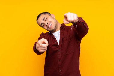 Asyalı yakışıklı bir adam sarı arka planda izole edilmiş. Avucunun içinde hayali bir ilan tutuyor.