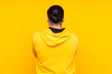 Asyalı yakışıklı adam sarı arka planda izole edilmiş bir şey gösteriyor.